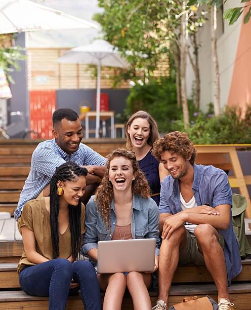 A shot of university students sharing a laptop on campus