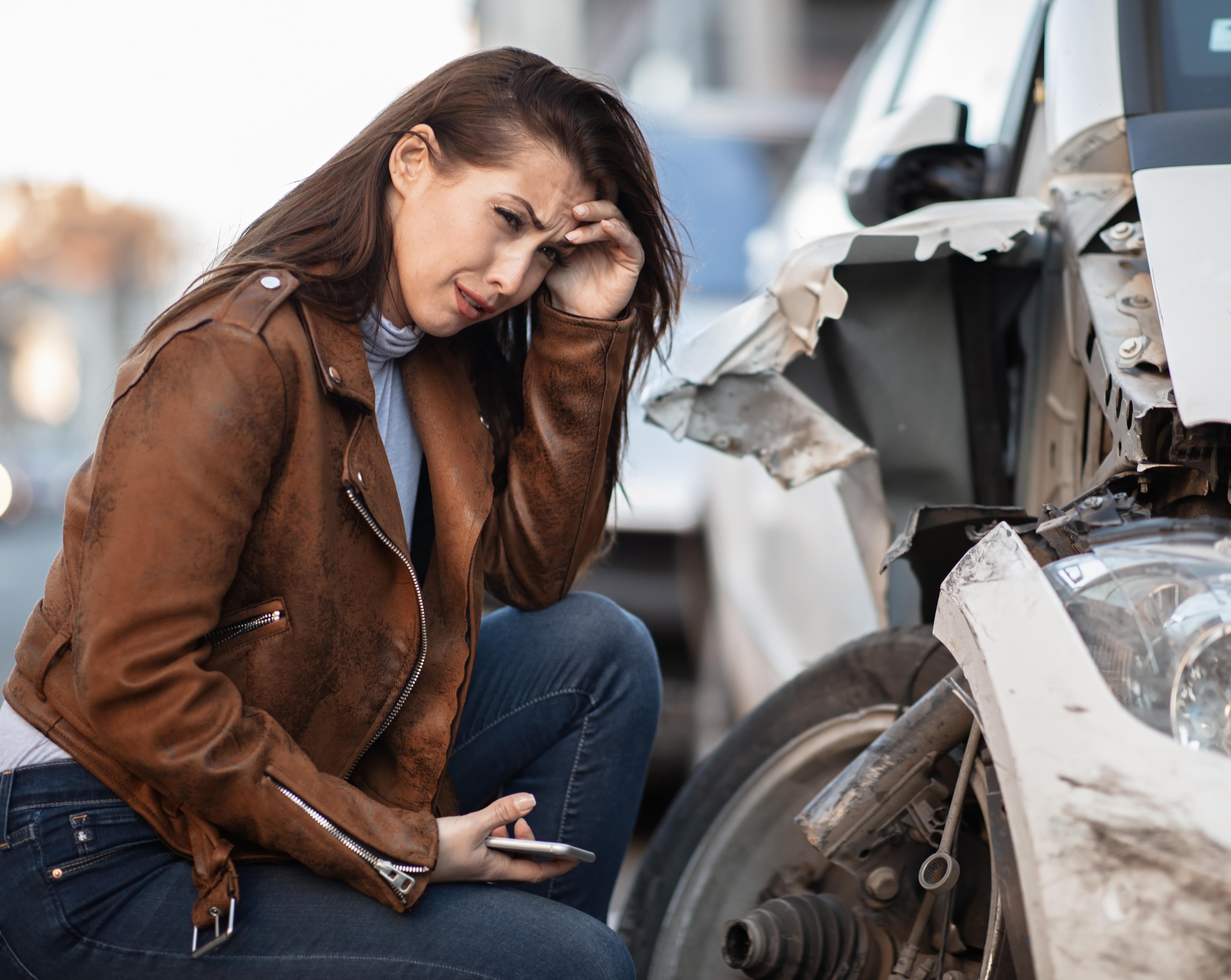 Young desperate woman next to a crashed car.